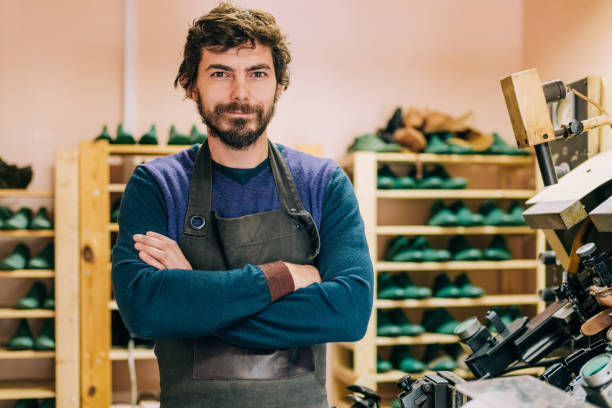 Portrait of male shoemaker. Shot of young craftsperson standing with crossed arms and looking at camera in his workshop. shoe mold stock pictures, royalty-free photos & images
