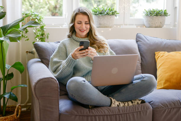 istock attractive middle aged woman sitting on the sofa ( Video Conference,  laptop) 1352105553