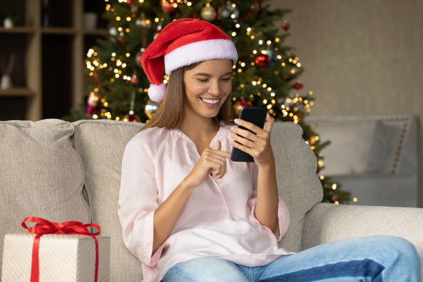 istock Happy girl in Santa assistant hat typing text on smartphone 1352106065