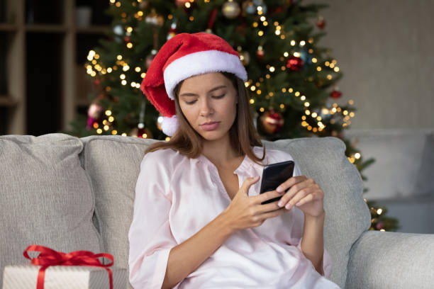 istock Sad thoughtful Xmas girl typing text message on smartphone 1352106422