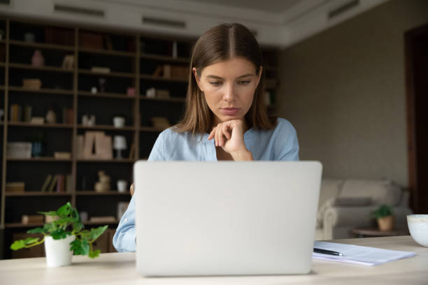 istock Serious pensive young employee working at laptop from home 1352106471