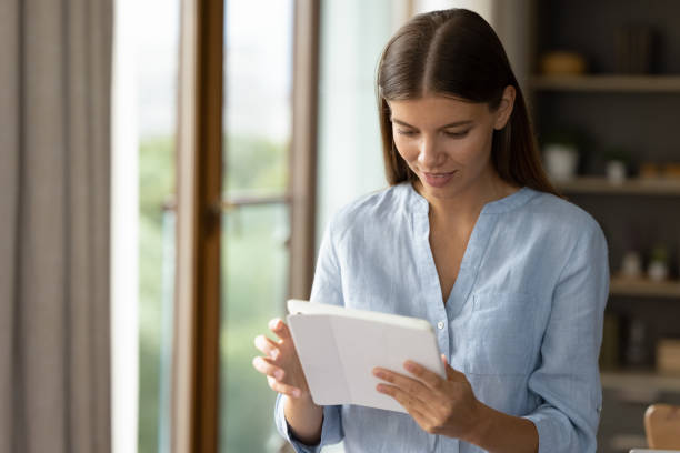 istock Focused young millennial girl using tablet computer, standing at home 1352106484
