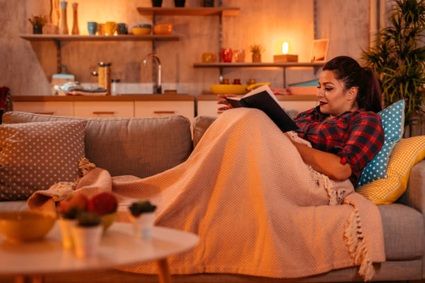 istock Woman At Home sitting on sofa and reading book 1352107737