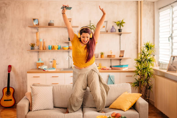 istock Woman singing and dancing on sofa at home 1352110130