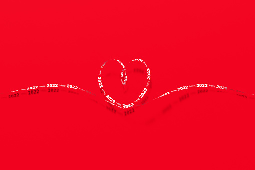 Happy 2022 written white heart shaped ribbon sitting on red background. Horizontal composition with copy space. Happy 2022 concept.