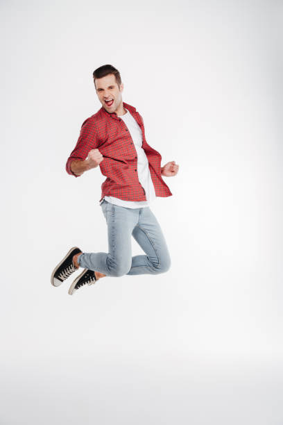 istock Vertical image of happy man jumping in studio 1352110788