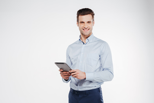 Smiling business man which holding tablet computer in hand and looking at camera. Isolated white background