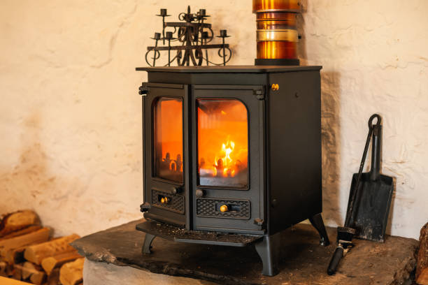 istock Shallow focus on an iron stove with a real wood fire glowing inside it. 1352112818