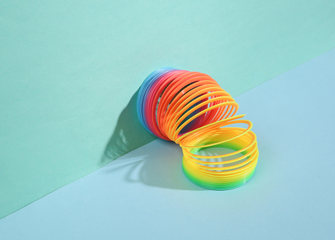Rainbow plastic multicolored spiral toy with geometric shapes on blue background. Minimalism. Creative still life