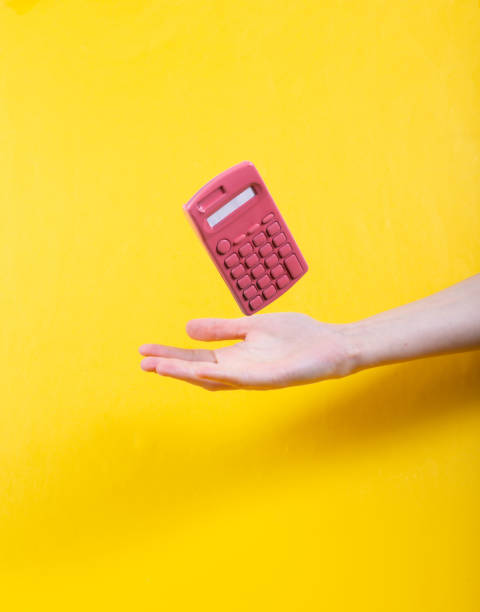 ручной и левитирующих розовый калькулятор на желтом фоне. минималистичный натюрморт. концепт-арт - hand calculator стоковые фото и изображения
