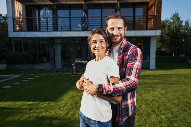 istock Bearded handsome man hugging his girlfriend while in front of the modern house 1352115011