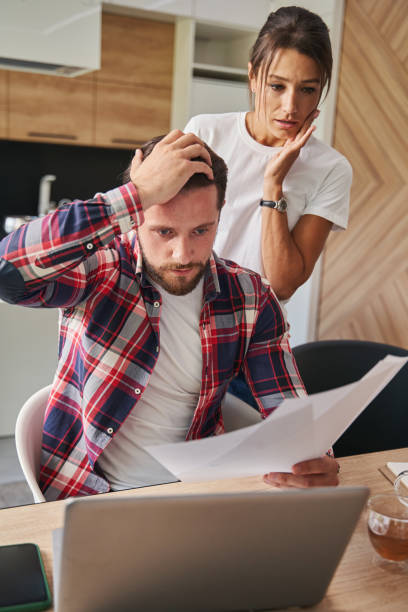 istock Depressed bearded man with partnership report working on laptop in home office 1352115106