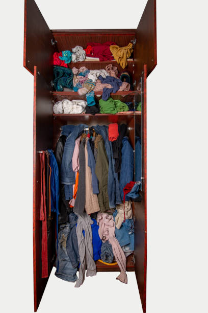 istock Isolated open wardrobe with clothes on hangers and clutter in open drawers. Open wardrobe with clothes on a white background 1352117210