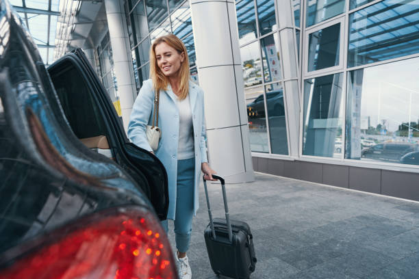 自動車の前に立っている手荷物を持つ女性の乗客 - タクシー ストックフォトと画像