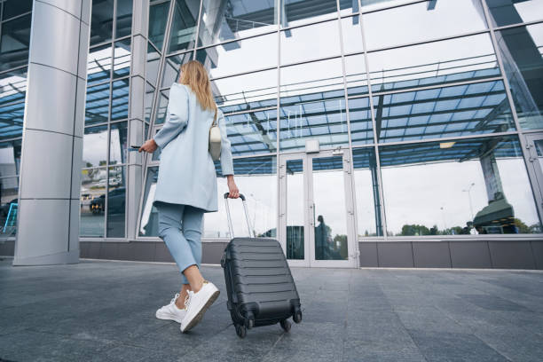 istock Fashionable passenger holding trolley suitcase at telescopic handle 1352121718
