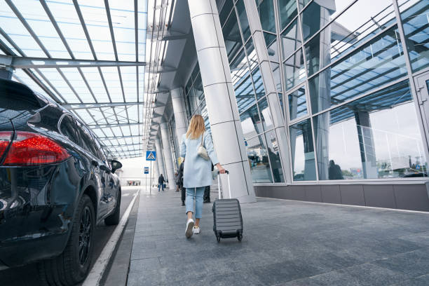 istock Stylish passenger trundling her trolley suitcase by telescopic metal handle 1352121721