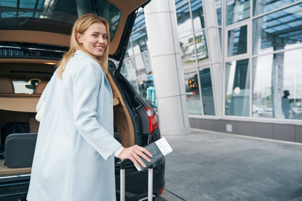 istock High-spirited passenger with luggage standing near open car trunk 1352121838