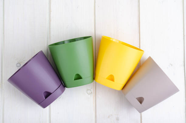 Empty colored plastic flower pots on wooden background. Studio Photo