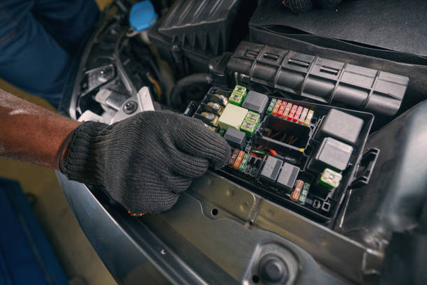 Automobile technician getting car fuse out of box in engine compartment with hand