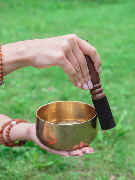 istock singing bowl and stick in woman's hands with bracelets. Bowl touching moment 1352126462