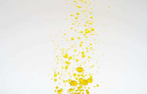 Photo of Oil drops isolated. Golden liquid drops of oil in water on a white background. Food or cosmetics component.