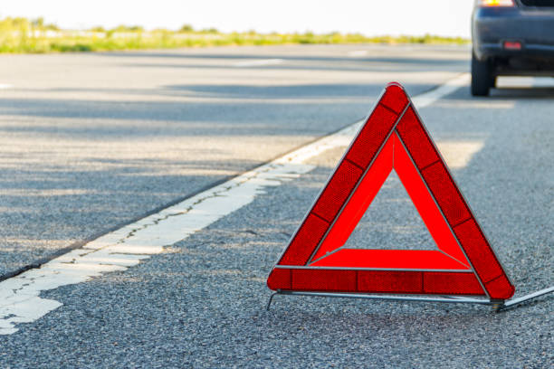 istock Red emergency stop sign (red triangle warning sign) and broken car on road 1352128508