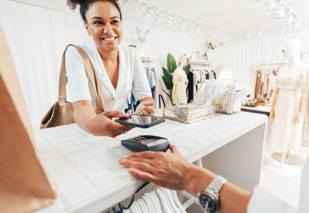 istock Happy customer paying through smartphone at a counter in a clothing store 1352128653