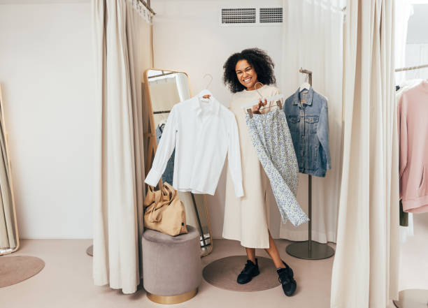 istock Happy woman standing with clothes in fitting room 1352128668