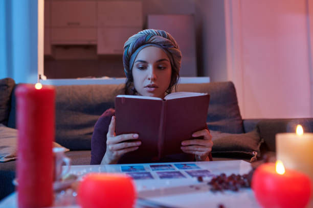 Beginner Tarot card reader in headwear reading a fortune-telling handbook