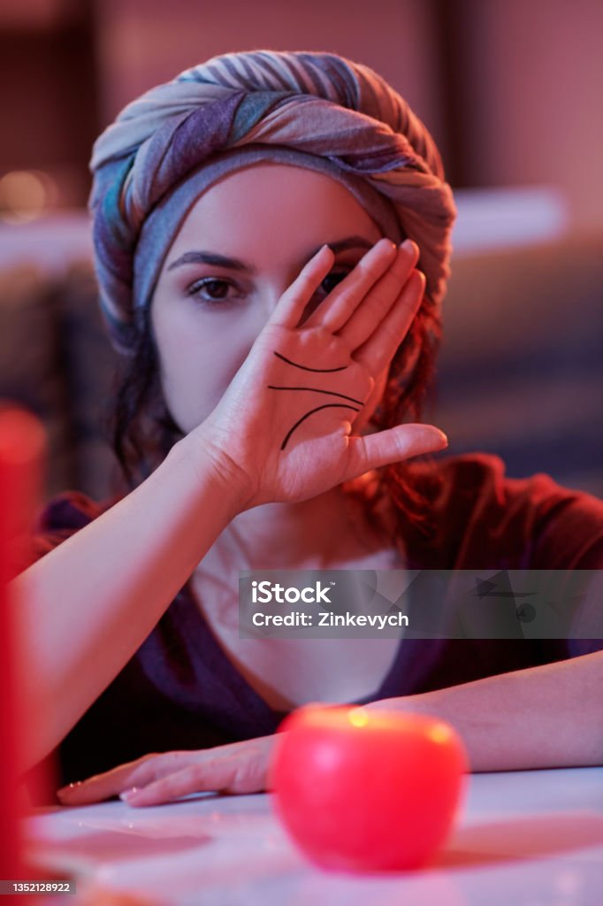 Chiromancer demonstrating her hand with palmar creases Adult Caucasian female fortune-teller in the headwear showing lines on her palm before the camera 25-29 Years Stock Photo