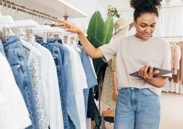 istock Young boutique owner taking inventory standing at rack with digital tablet 1352129133