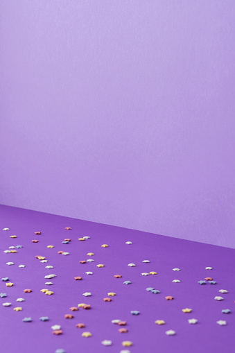 Purple background from one wall and floor, multicolored stars on the floor, holiday concept or birthday