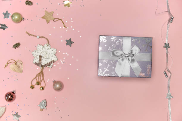 istock Top view of a silver-colored Christmas gift with a bow. Pink background. 1352130478