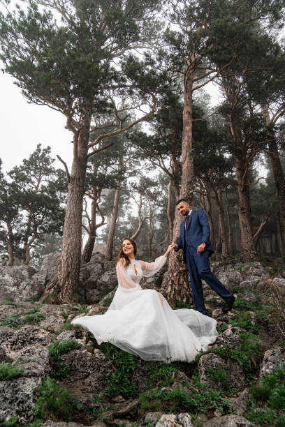 istock bride and groom holding hands in a mysterious misty mountain forest. 1352131276