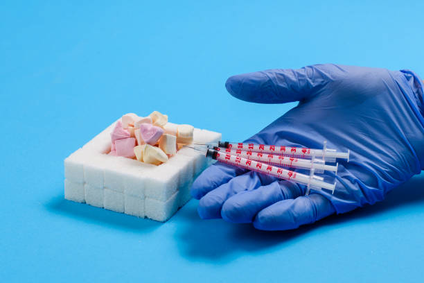 diverse siringhe per un diabetico nella mano del medico accanto a zucchero e dolci su uno sfondo blu. - insulin resistance foto e immagini stock