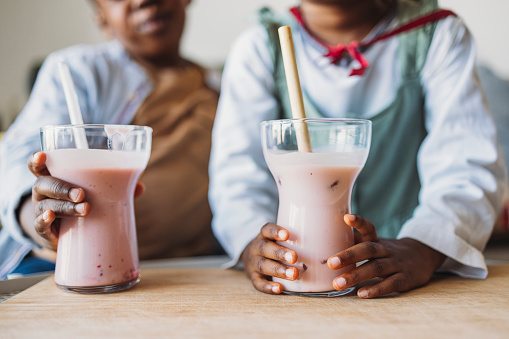 Unrecognizable brother and sister holding a strawberry smoothie in hands