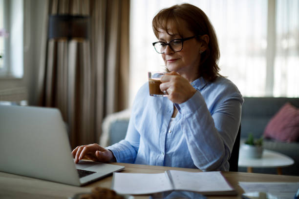 istock Smiling senior woman drinking coffee while working at home 1352133444
