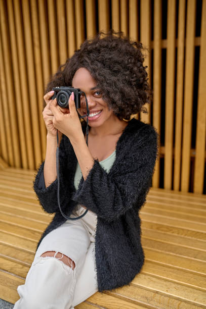 istock Curly-haired female photographer with camera in hands 1352133941