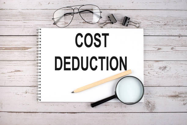 istock Notebook with text COST DEDUCTION on wooden table with pen, magnifier and glasses 1352134870