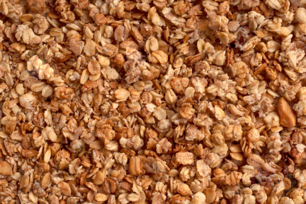 Texture of organic homemade baked granola with oats and nuts Organic granola with oats, raisins, nuts. Texture of brown muesli flakes as background. Top view. Blank space for text. A backdrop of vegetarian and vegan food for breakfast. Healthy nutrition concept granola photos stock pictures, royalty-free photos & images