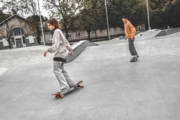 istock Girl riding skateboard in front and guy behind 1352138069