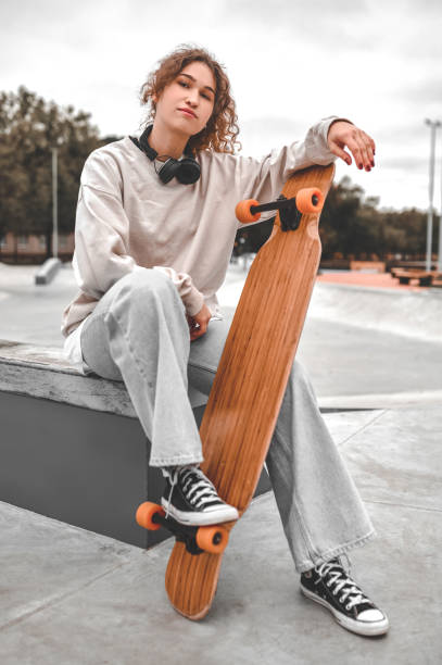 istock Girl with skateboard sitting in park 1352138099
