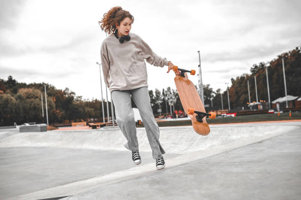 istock Girl jumping off skateboard in park 1352138111
