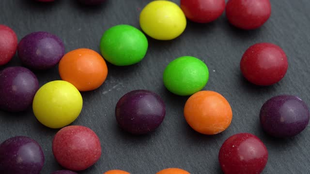 Colored fruit candies rotate on a black background, colored marco sweets