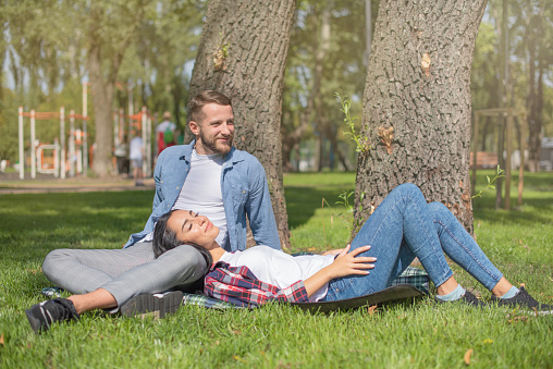 Couple in love are resting in the park and hugging. Attractive guy and beautiful young girl romantic pastime.