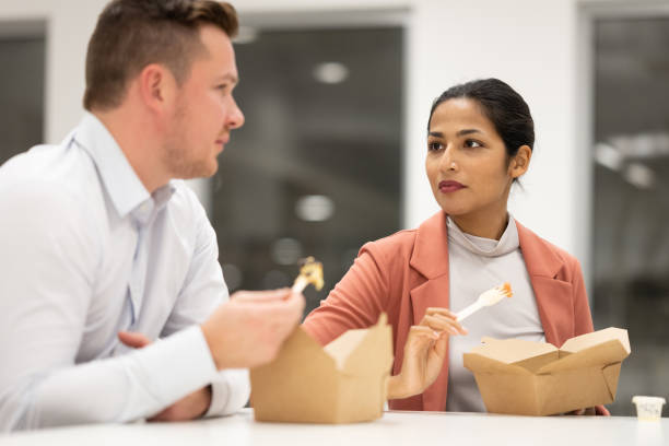 istock Colleagues eating from to-go boxes in company cafeteria 1352139187