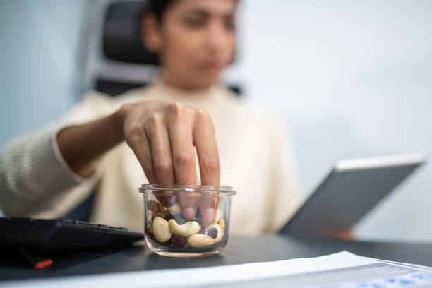 Indian woman using a digital tablet while holding nuts in hand stock photo