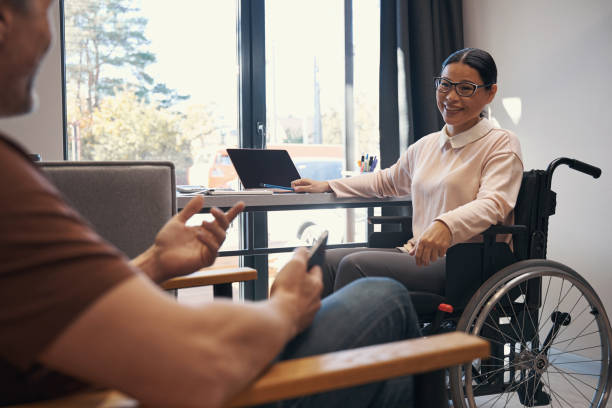istock Jolly woman with disability talking with man in office 1352139692
