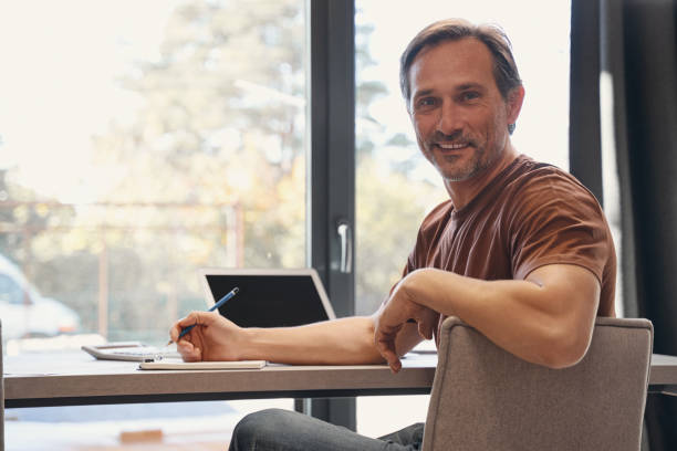 istock Happy mature businessman working with notebook indoors 1352139701