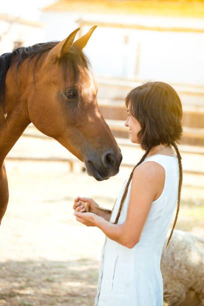 istock Girl with dreadlocks stroking her brown horse. 1352139759